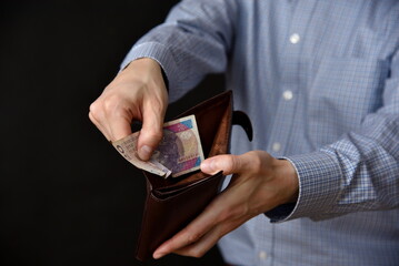 Mezczyzna trzymajacy polskie banknoty, gotowka w portfelu.