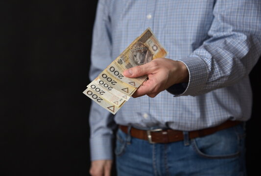 Mezczyzna trzymajacy polskie banknoty, gotowka. Plik banknotow 200 zlotych.