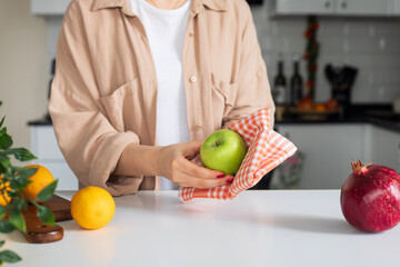Woman wiping green apple with kitchen towel, closeup