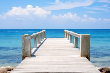 a wooden dock with railings leading to the ocean - obrazy, fototapety, plakaty
