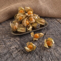 Physalis peruviana. Edible golden berries of physalis on old wooden background, still life. 