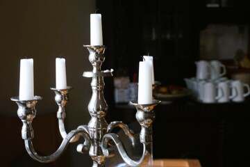 Innenausstattung mit altertümlichem silbernen Kerzenständer mit weißen Kerzen vor braunem alten...