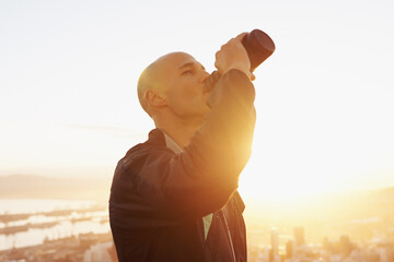 Man, fitness and drinking water with sunset for natural sustainability, break or outdoor hydration....