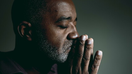 Earnest African American Elder Seeking Divine Guidance in Prayer, Eyes Shut and Hands Together,...