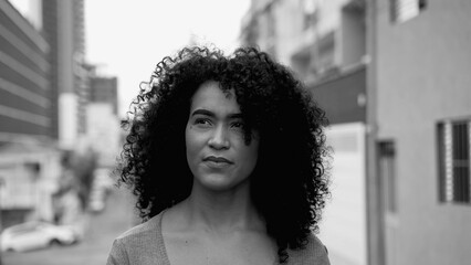 Empowered Young Brazilian Woman with Curly Hair Striding in City Street in intense black and white....