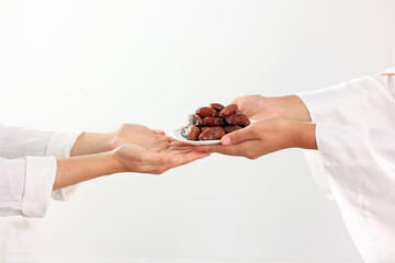Female Muslim Hand Over A Plate of Dates Fruit to Other.