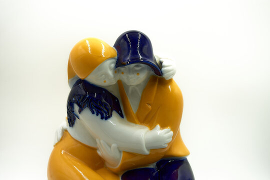 Figure of yellow, blue and white Galos dedicated to love where a sitting couple holds each other and puts their faces together