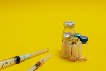 photo of several vials of injection medicine and syringes isolated on a yellow background