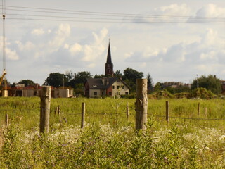 Church tower, meadows, fields and wooden posts