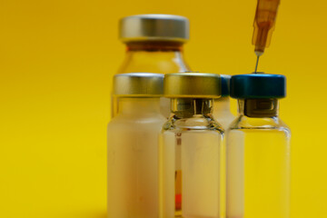 photo of several vials of injection medicine and syringes isolated on a yellow background