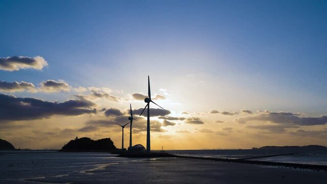풍력 발전기가 있는 해지는 바닷가 풍경