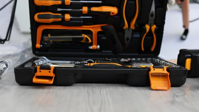 Male craftsman opens a set of tools in a suitcase on the floor.