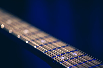 Part of an acoustic guitar, guitar fretboard on a black background.