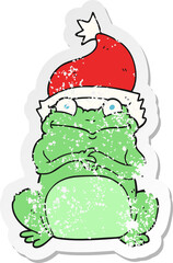 retro distressed sticker of a cartoon frog wearing christmas hat