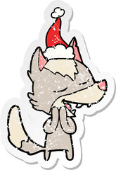 distressed sticker cartoon of a wolf laughing wearing santa hat