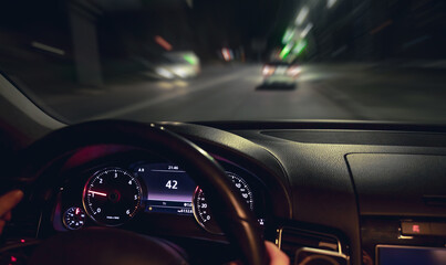 Car steering wheel and view of the night road from the car, close-up.