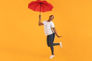 Fototapeta na wymiar black lady holding a red umbrella poses standing in studio