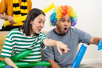 Happy asian diverse group friends watching soccer games world cup competition on television...