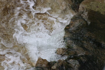 A view from above a waterfall in a large urban creek is seen from above looking downward. A bridge afforded the view.