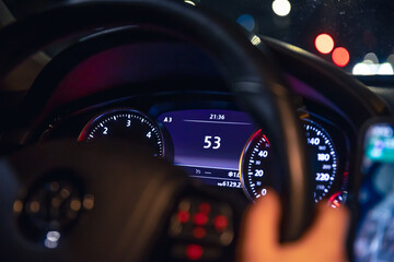 Speed indication and women's hands on the steering wheel in a car at night.