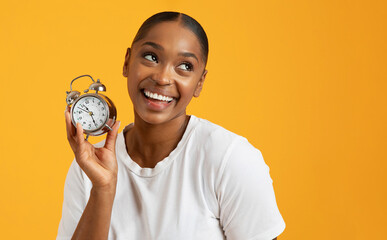 Cheerful black millennial woman holding alarm clock on yellow background