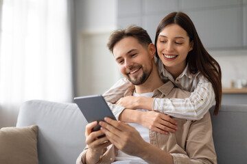 Happy couple enjoying time with digital tablet on couch