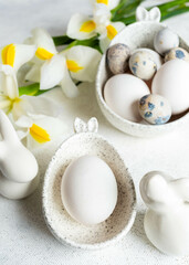 Fototapeta na wymiar Easter natural colors eggs in bowls with bunny ears, bunnies, white Iris flowers on white close up.