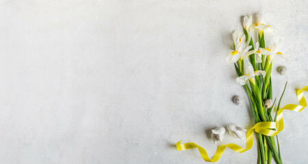 Bouquet of white Iris flowers, yellow ribbon, quail eggs, small ceramic bunnies on white Copy space