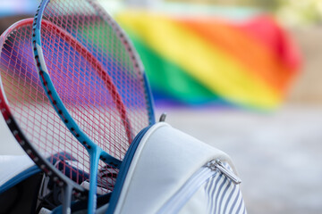 Badminton sport equipments, rackets and sportbag placed on floor with blurred rainbow flag...