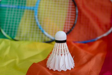 White cream badminton shuttlecock ball on rainbow flag and badminton rackets background, concept...