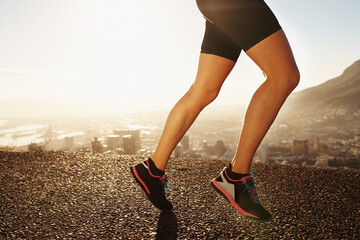 Legs, shoes and person running in city, cardio and fitness for health and wellness at sunrise. Athlete, marathon and speed with runner on road outdoor for exercise, workout and training in morning