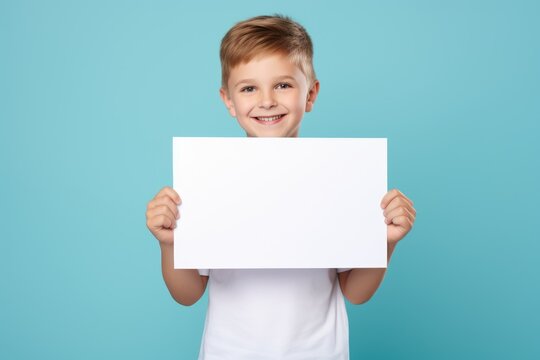 a handsome boy holding a blank placard sign poster paper for mock up in his hands