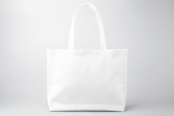 Empty white canvas tote bag with handles presented on a neutral grey backdrop. Blank White Tote Bag Isolated on Grey Background