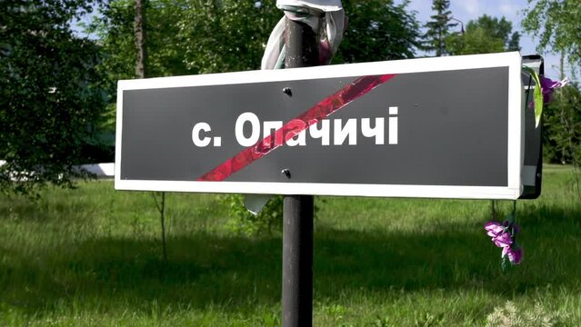 Chernobyl sign. The name of the destroyed village of Opachychi is written in white letters on a black board. The Chernobyl tragedy: Abandoned, destroyed villages.