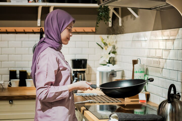 Young asian woman in hijab cooking in the kitchen