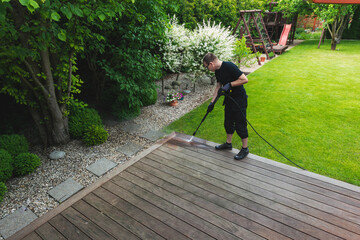 man cleaning terrace with a power washer - high water pressure cleaner on wooden terrace surface - 751507399