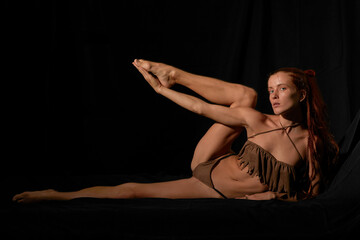 Red hair cauasian girl acting in yoga black isolated