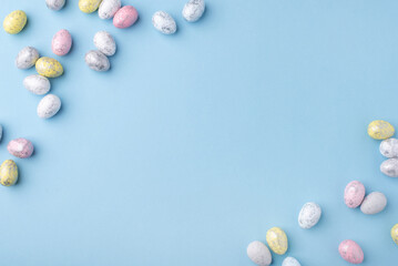 Festive Easter background. Multicolored Easter eggs on a blue table. Card with a place for text. Top view.