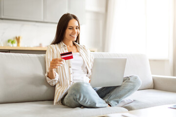 Woman with credit card making an online purchase from laptop at home