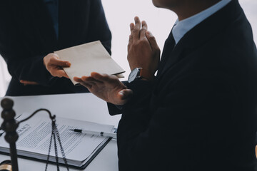 Justice and Law concept. Legal counsel presents to the client a signed contract with gavel and legal law or legal having team meeting at law firm in background