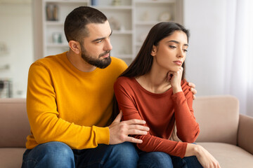 Compassionate young man comforting his upset wife at home