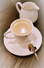 Cup with coffee and milk jug in sepia tone.