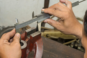 Close up scene the machine operator measuring dimension of cast iron parts by Vernier caliper.