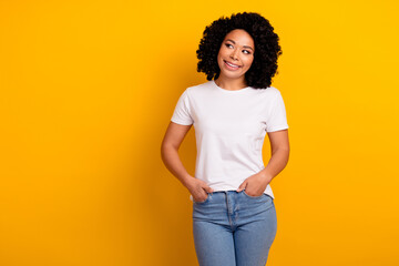 Portrait of good mood girl with curly hairstyle wear white t-shirt look at sale empty space isolated on vivid yellow color background