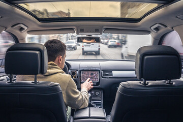 Man touching screen of a GPS navigation system in his car.