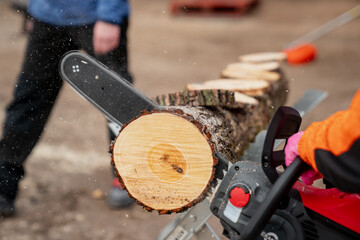 Chainsawing wooden log with battery powered chain saw tool