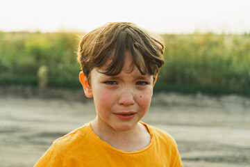 Portrait of a boy in nature. A boy in an orange T-shirt is crying in nature. Non-positive child,...