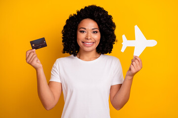 Photo of positive excited woman wear white t-shirt buying online plane tickets isolated yellow...