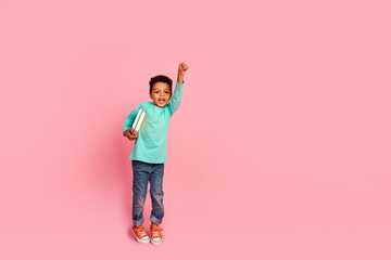 Full length photo of adorable little boy raise fist superhero hold books wear trendy aquamarine garment isolated on pink color background
