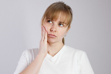 woman 30s has a toothache, holding her cheek